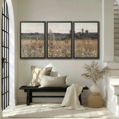 A loose painterly meadow with scattered blue and white wildflowers 3 piece framed canvas wall art displayed in a entryway