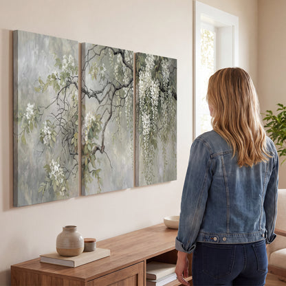 Trailing white blossoms and delicate green branches on pale gray 3 piece canvas wall art three panel arrangement on a wall