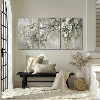 Trailing white blossoms and delicate green branches on pale gray 3 piece canvas wall art displayed in a entryway