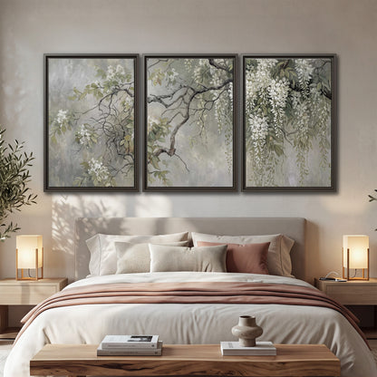 Trailing white blossoms and delicate green branches on pale gray 3 piece framed canvas wall art displayed in a bedroom