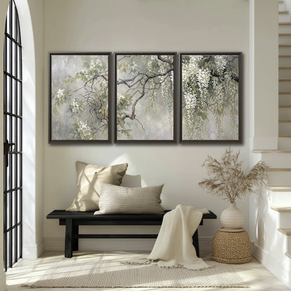 Trailing white blossoms and delicate green branches on pale gray 3 piece framed canvas wall art displayed in a entryway