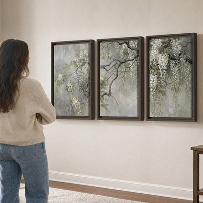 Trailing white blossoms and delicate green branches on pale gray 3 piece framed canvas wall art three panel arrangement on a wall