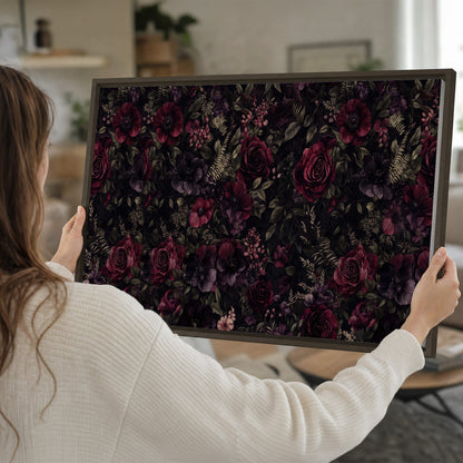Deep burgundy roses and small pale flowers on a dark background single framed canvas wall art held in hands