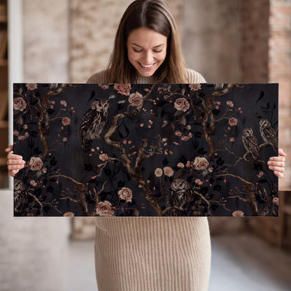 Owls among curling branches and dusty pink flowers on dark gray single canvas wall art held in hands