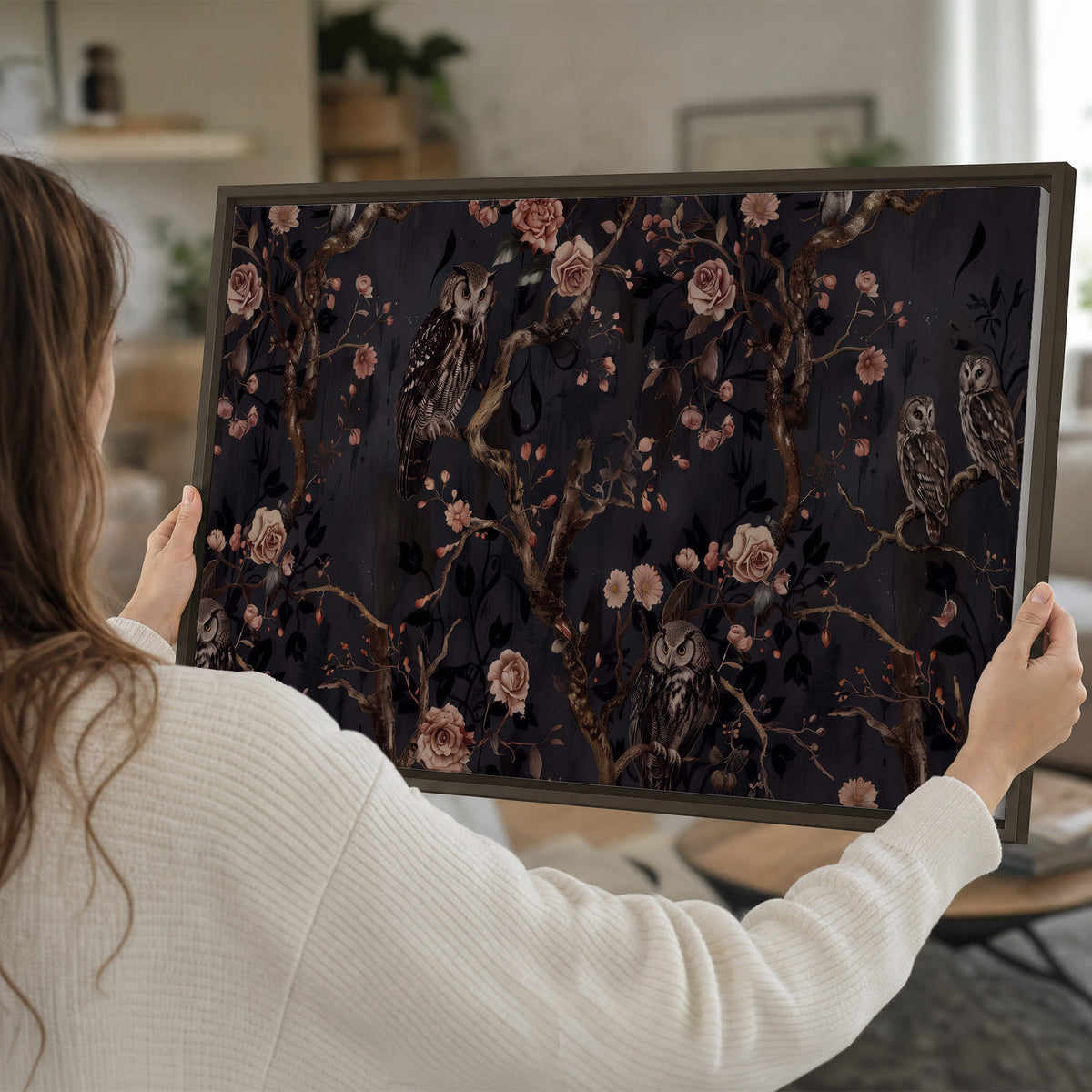 Owls among curling branches and dusty pink flowers on dark gray single framed canvas wall art held in hands