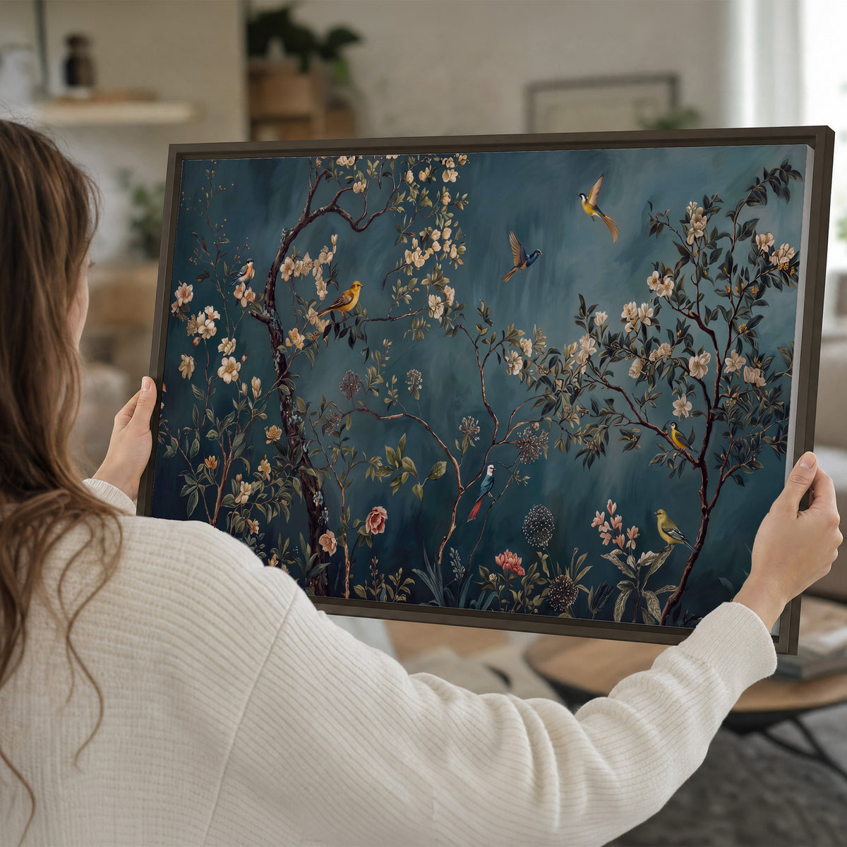 Colorful birds and pale blossoms on branches against teal blue single framed canvas wall art held in hands