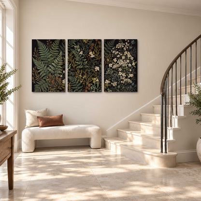 Layered green ferns and delicate cream flowers on a black background 3 piece canvas wall art styled in an interior