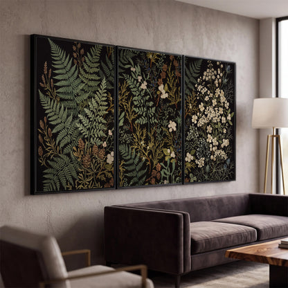 Layered green ferns and delicate cream flowers on a black background 3 piece framed canvas wall art displayed in a modern living room