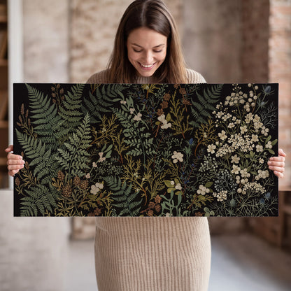 Layered green ferns and delicate cream flowers on a black background single canvas wall art held in hands