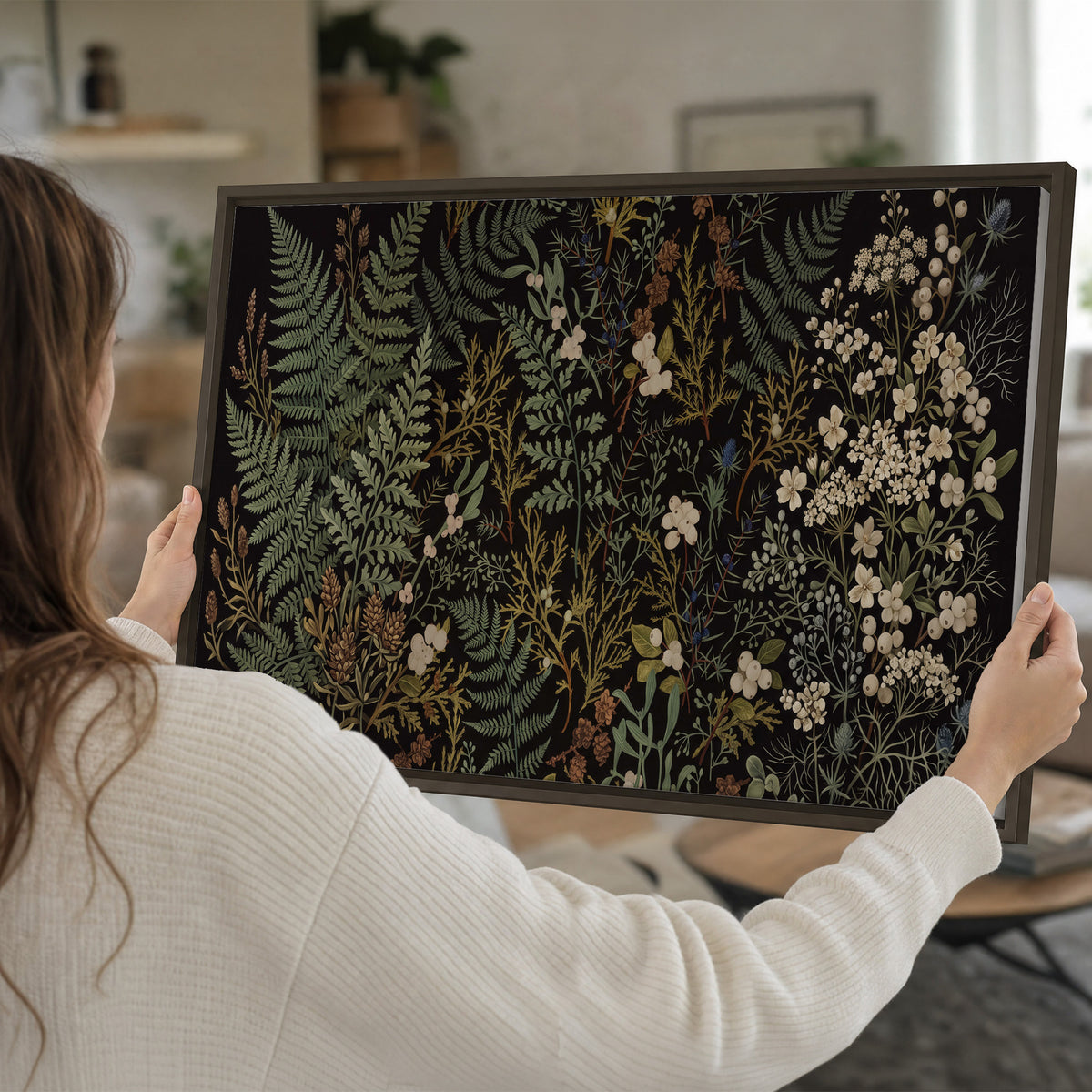 Layered green ferns and delicate cream flowers on a black background single framed canvas wall art held in hands