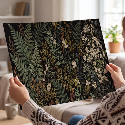 Layered green ferns and delicate cream flowers on a black background single poster print held in hands