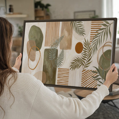 Green botanical leaves layered with ochre and cream geometric forms single framed canvas wall art held in hands