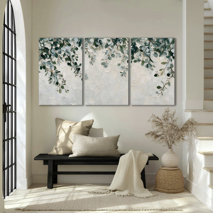 Soft green eucalyptus branches on a cream background 3 piece canvas wall art displayed in a entryway