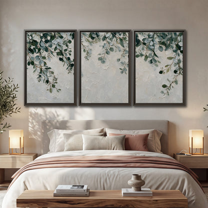 Soft green eucalyptus branches on a cream background 3 piece framed canvas wall art displayed in a bedroom