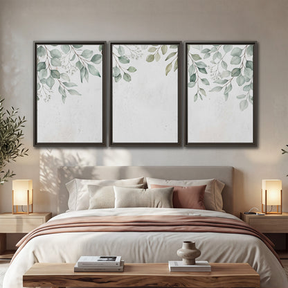 Pale sage eucalyptus leaves against a light background 3 piece framed canvas wall art displayed in a bedroom