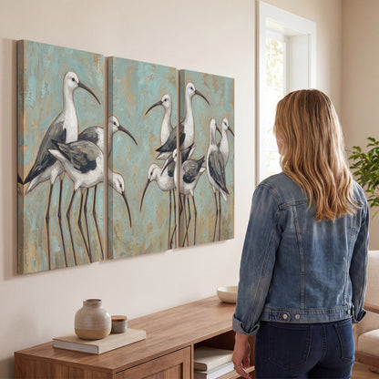 Long-legged white and gray wading birds against a muted aqua background 3 piece canvas wall art three panel arrangement on a wall