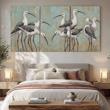 Long-legged white and gray wading birds against a muted aqua background 3 piece canvas wall art displayed in a bedroom