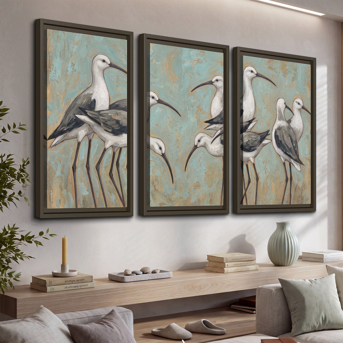 Long-legged white and gray wading birds against a muted aqua background 3 piece framed canvas wall art displayed in a console