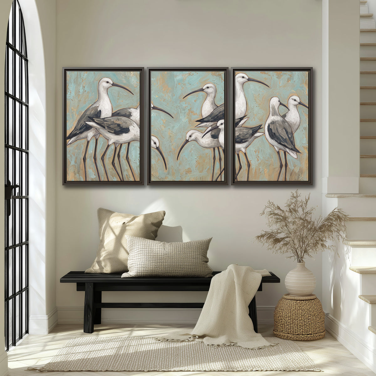 Long-legged white and gray wading birds against a muted aqua background 3 piece framed canvas wall art displayed in a entryway