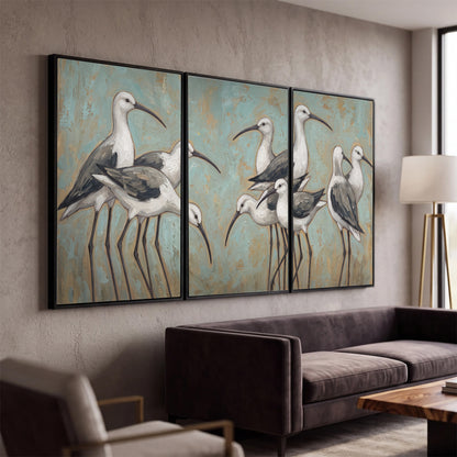 Long-legged white and gray wading birds against a muted aqua background 3 piece framed canvas wall art displayed in a modern living room