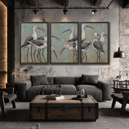 Long-legged white and gray wading birds against a muted aqua background 3 piece framed canvas wall art displayed in a industrial room