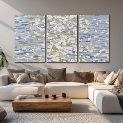 Loose pale blue, white and soft green marks suggesting shimmering water 3 piece canvas wall art displayed in a living room