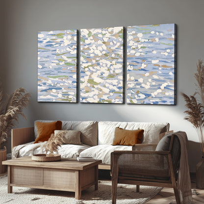 Loose pale blue, white and soft green marks suggesting shimmering water 3 piece canvas wall art displayed in a rustic living room