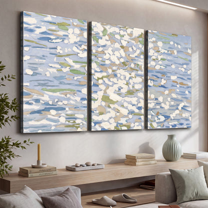 Loose pale blue, white and soft green marks suggesting shimmering water 3 piece canvas wall art displayed in a console