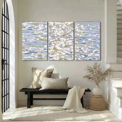 Loose pale blue, white and soft green marks suggesting shimmering water 3 piece canvas wall art displayed in a entryway