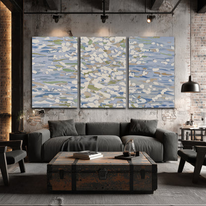 Loose pale blue, white and soft green marks suggesting shimmering water 3 piece canvas wall art displayed in a industrial room