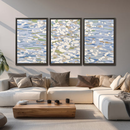 Loose pale blue, white and soft green marks suggesting shimmering water 3 piece framed canvas wall art displayed in a living room