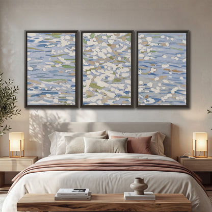 Loose pale blue, white and soft green marks suggesting shimmering water 3 piece framed canvas wall art displayed in a bedroom
