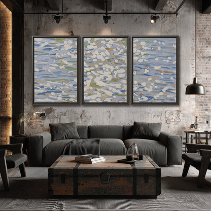 Loose pale blue, white and soft green marks suggesting shimmering water 3 piece framed canvas wall art displayed in a industrial room
