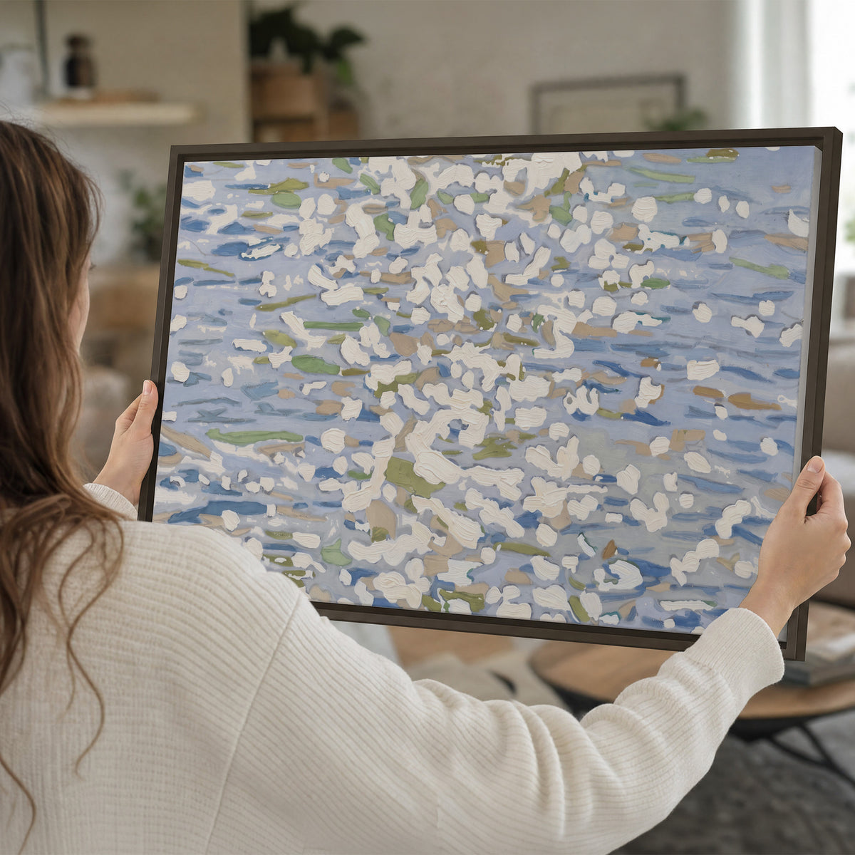 Loose pale blue, white and soft green marks suggesting shimmering water single framed canvas wall art held in hands