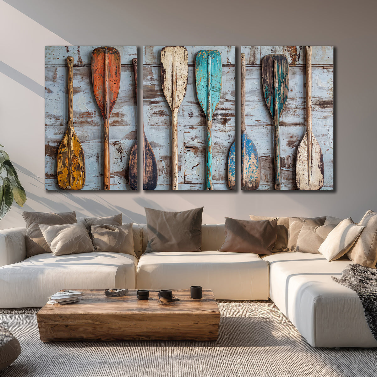 A row of colorful weathered wooden oars against pale blue boards 3 piece canvas wall art displayed in a living room