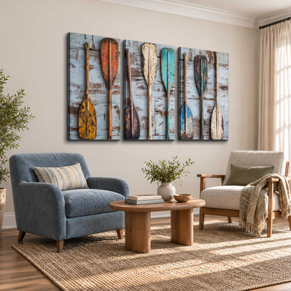 A row of colorful weathered wooden oars against pale blue boards 3 piece canvas wall art styled in an interior