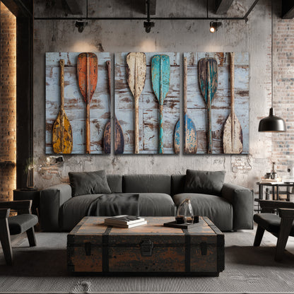 A row of colorful weathered wooden oars against pale blue boards 3 piece canvas wall art displayed in a industrial room
