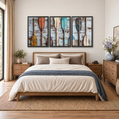A row of colorful weathered wooden oars against pale blue boards 3 piece framed canvas wall art styled in an interior