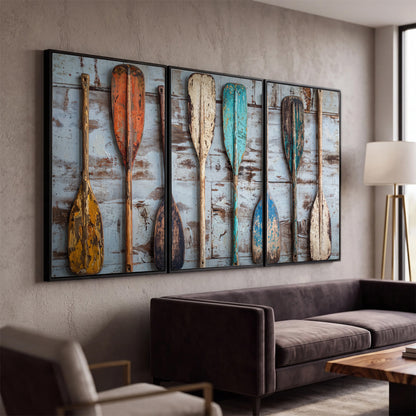 A row of colorful weathered wooden oars against pale blue boards 3 piece framed canvas wall art displayed in a modern living room