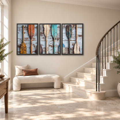 A row of colorful weathered wooden oars against pale blue boards 3 piece framed canvas wall art styled in an interior