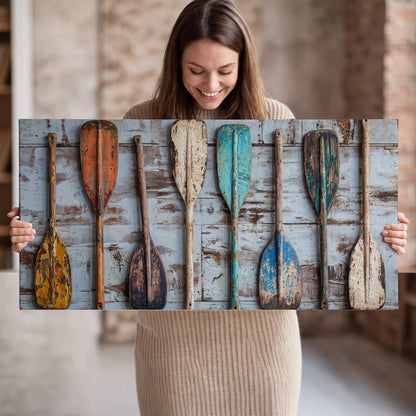 A row of colorful weathered wooden oars against pale blue boards single canvas wall art held in hands
