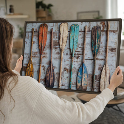A row of colorful weathered wooden oars against pale blue boards single framed canvas wall art held in hands