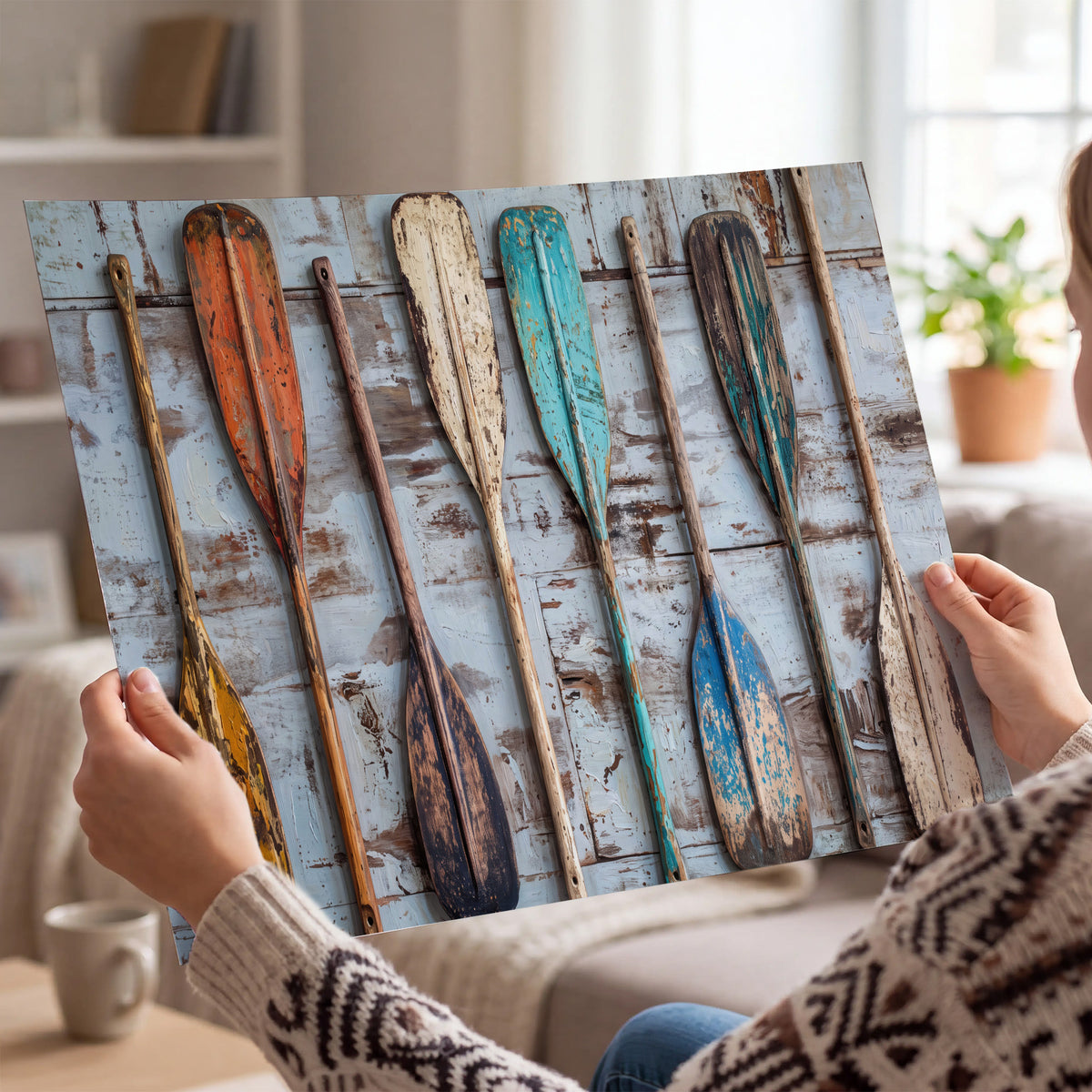 A row of colorful weathered wooden oars against pale blue boards single poster print held in hands