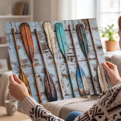 A row of colorful weathered wooden oars against pale blue boards single poster print held in hands
