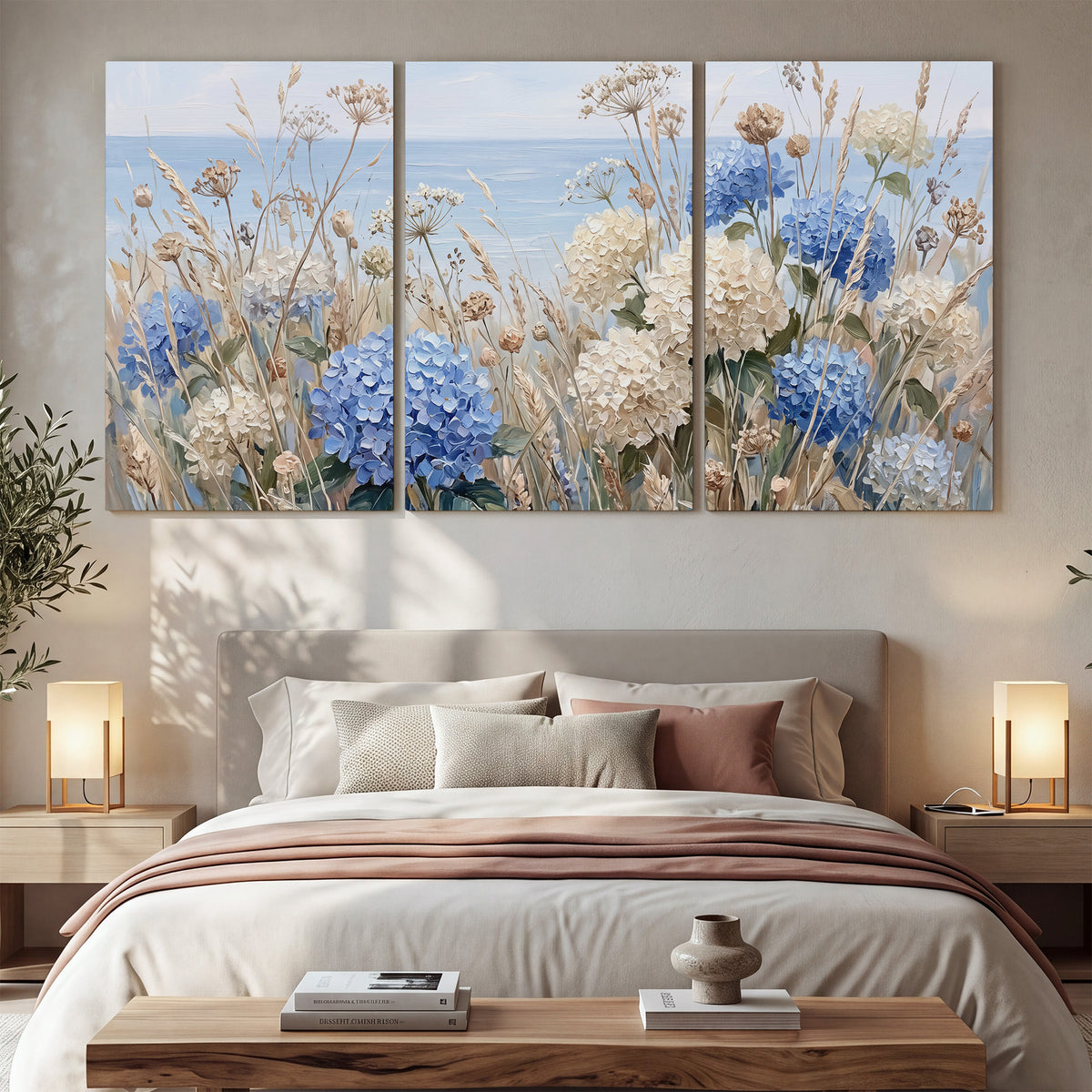 Blue hydrangeas and delicate ivory wildflowers beneath a pale blue sky 3 piece canvas wall art displayed in a bedroom