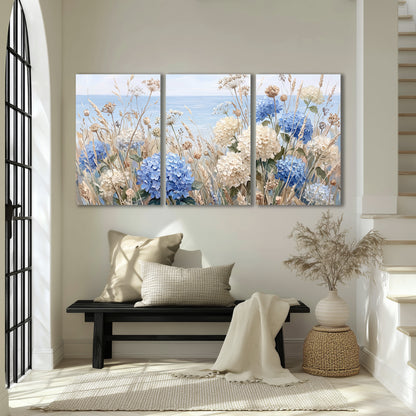 Blue hydrangeas and delicate ivory wildflowers beneath a pale blue sky 3 piece canvas wall art displayed in a entryway