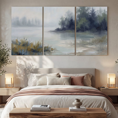 A calm pale lake bordered by dark evergreen trees and distant mist 3 piece canvas wall art displayed in a bedroom