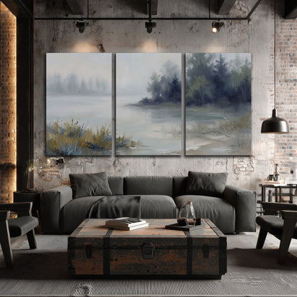 A calm pale lake bordered by dark evergreen trees and distant mist 3 piece canvas wall art displayed in a industrial room