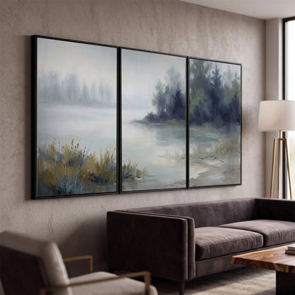 A calm pale lake bordered by dark evergreen trees and distant mist 3 piece framed canvas wall art displayed in a modern living room