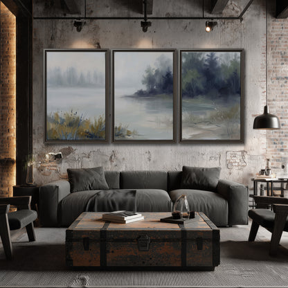 A calm pale lake bordered by dark evergreen trees and distant mist 3 piece framed canvas wall art displayed in a industrial room